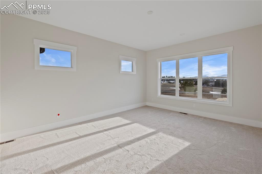 Empty room with baseboards, visible vents, and light colored carpet
