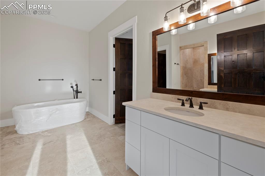 Bathroom with baseboards, a freestanding bath, and vanity