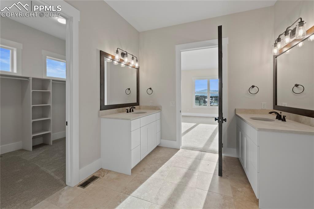 Bathroom with a sink, visible vents, two vanities, and plenty of natural light