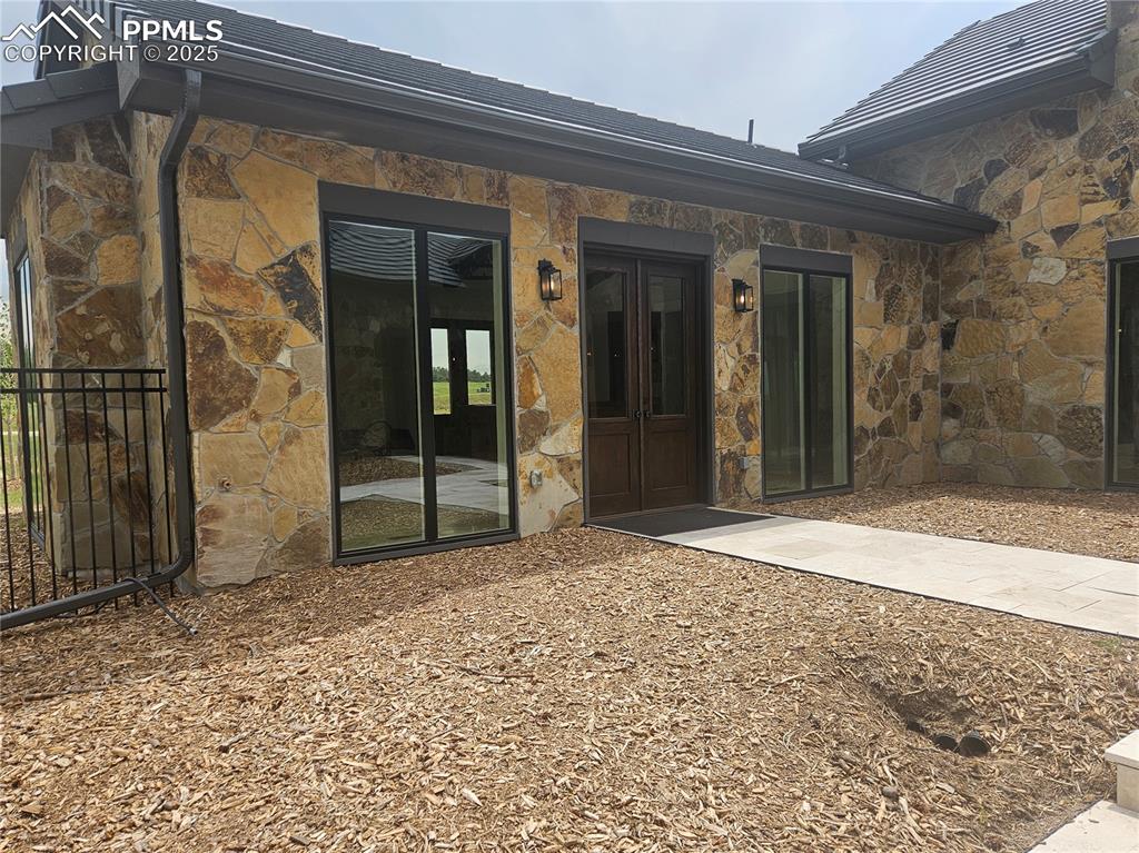 Back of house featuring stone siding and french doors