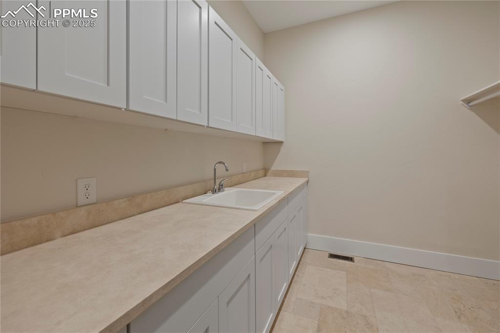Laundry area with a sink, baseboards, and visible vents