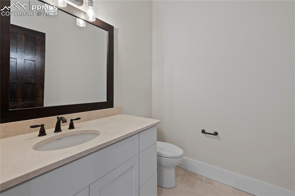 Bathroom featuring baseboards, toilet, and vanity