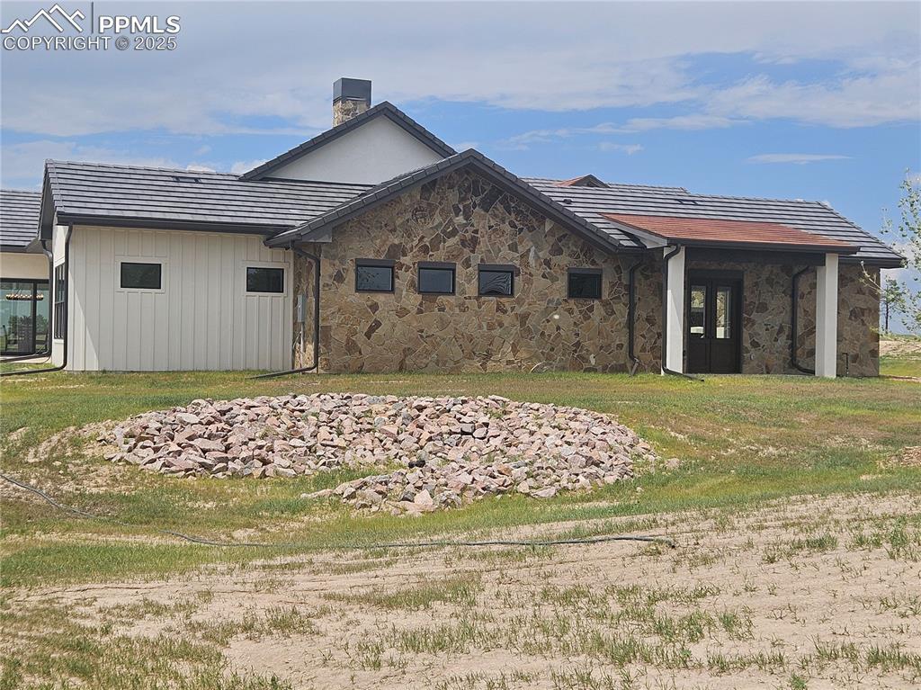Rear view of property with a chimney and stone siding