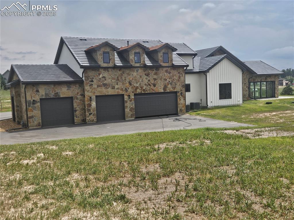 Modern farmhouse style home with driveway, a front yard, an attached garage, and board and batten siding