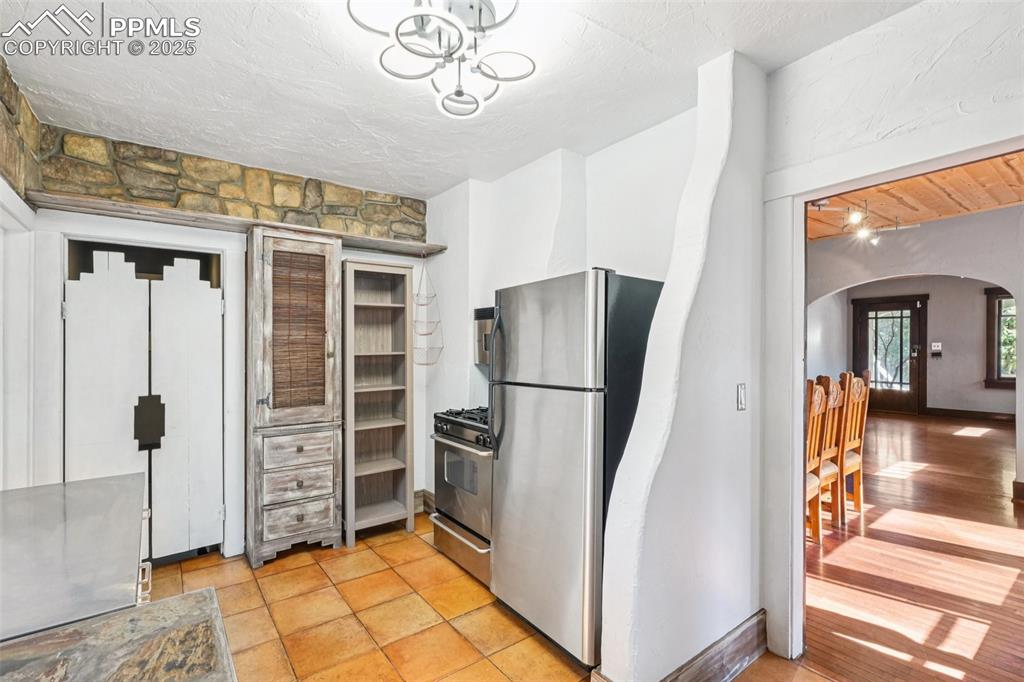Custom kitchen with gas burning stove, stone countertops and custom cabinetry with tile floors.
