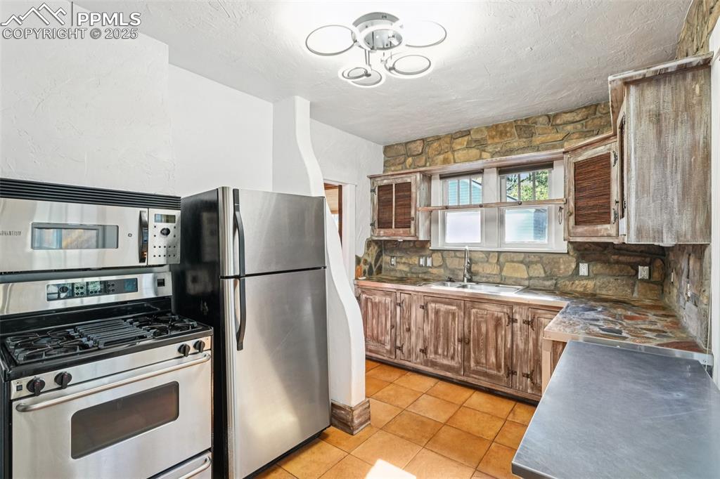 Custom kitchen with gas burning stove, stone countertops and custom cabinetry with tile floors.