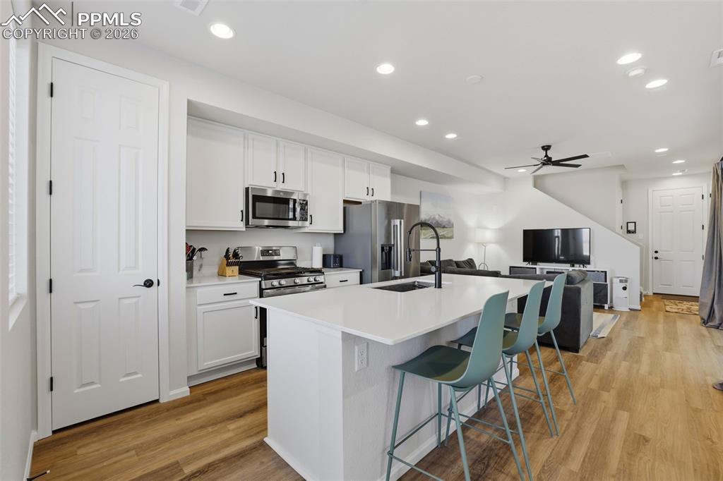 Kitchen featuring white cabinetry, a kitchen breakfast bar, a ceiling fan, a center island with sink, and recessed lighting