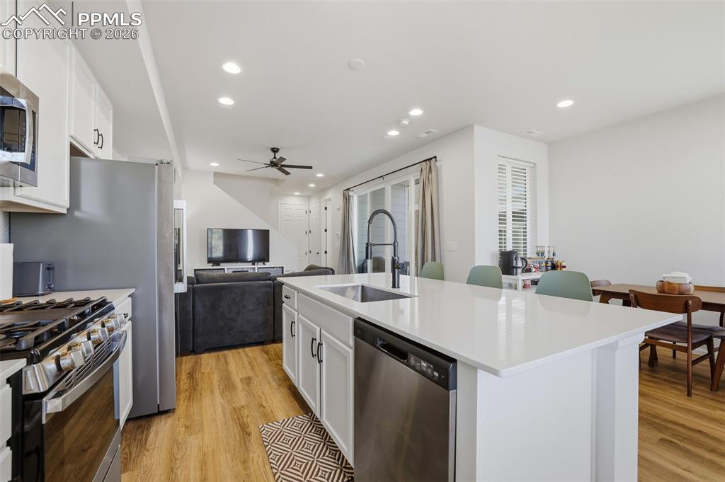 Kitchen featuring white cabinetry, open floor plan, appliances with stainless steel finishes, light wood-style flooring, and recessed lighting