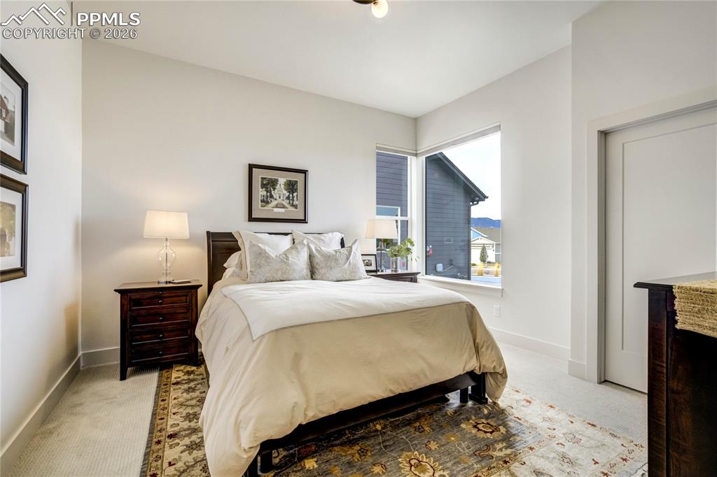 Secondary Main Level Bedroom: Ideally Positioned on the Main Level, This Light-Filled Bedroom Features Expansive Picture Windows That Invite Natural Light to Pour In, Creating an Airy and Inviting Atmosphere. A Generous Walk-In Closet Enhances Storage and Functionality, While Dimmable Lighting Allows the Space to Transition Effortlessly from Guest Retreat to Private Sanctuary