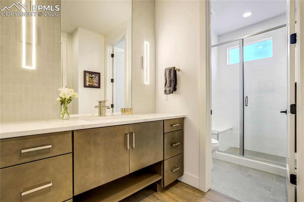 Main Level 3/4 Bath Thoughtfully Designed with Both Form and Function in Mind, the Main Level ¾ Bath Showcases Quartz Countertops, a Counter-to-Ceiling Backsplash, and Modern Lighting that Elevate the Space. The Floor-to-Ceiling Tiled Shower with Bench Seating Creates a Spa-Inspired Feel, While a Dedicated Linen Closet Adds Practical Storage. Dimmable Lighting Enhances Ambiance, Delivering a Polished and Adaptable Environment