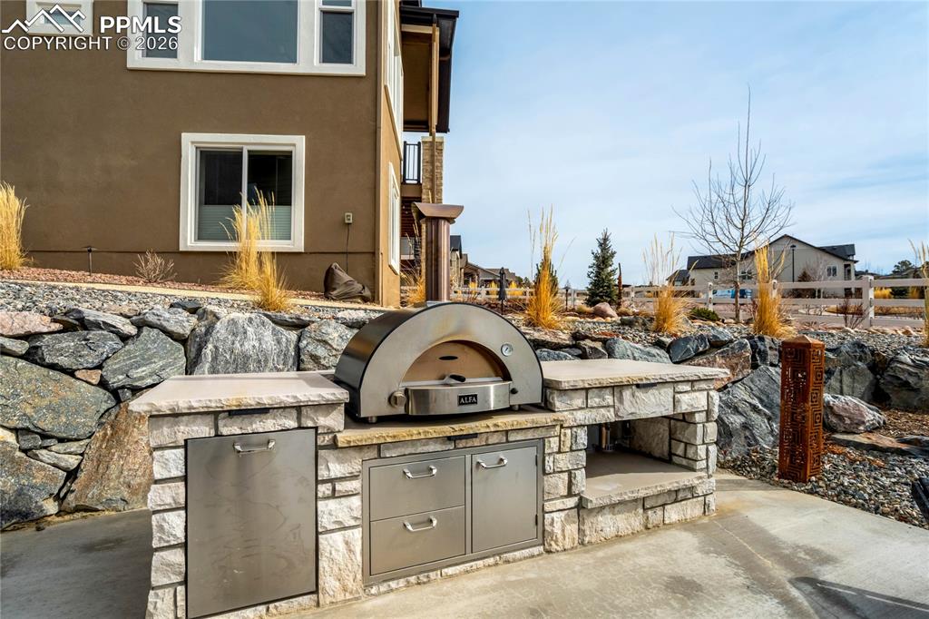 Outdoor living is fully realized with a built-in kitchen and dual-fuel pizza oven designed for elevated entertaining