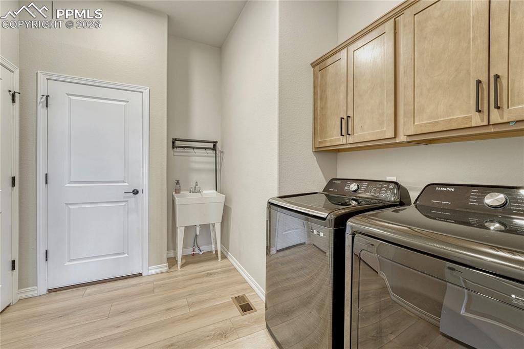 Mudroom and laundry, off of garage with sink and cabinetry.