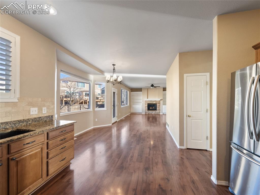 Kitchen with a chandelier, a fireplace, freestanding refrigerator, wood finish cabinets, and dark stone counters