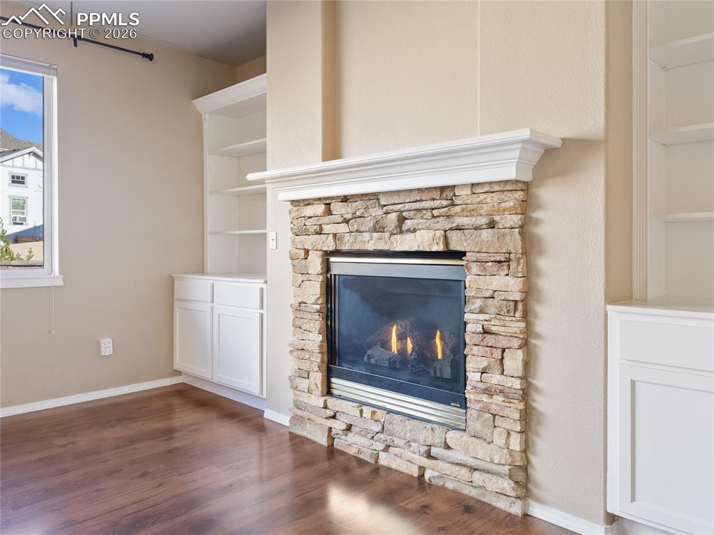 Detailed view of built in features, a stone fireplace, and wood finished floors