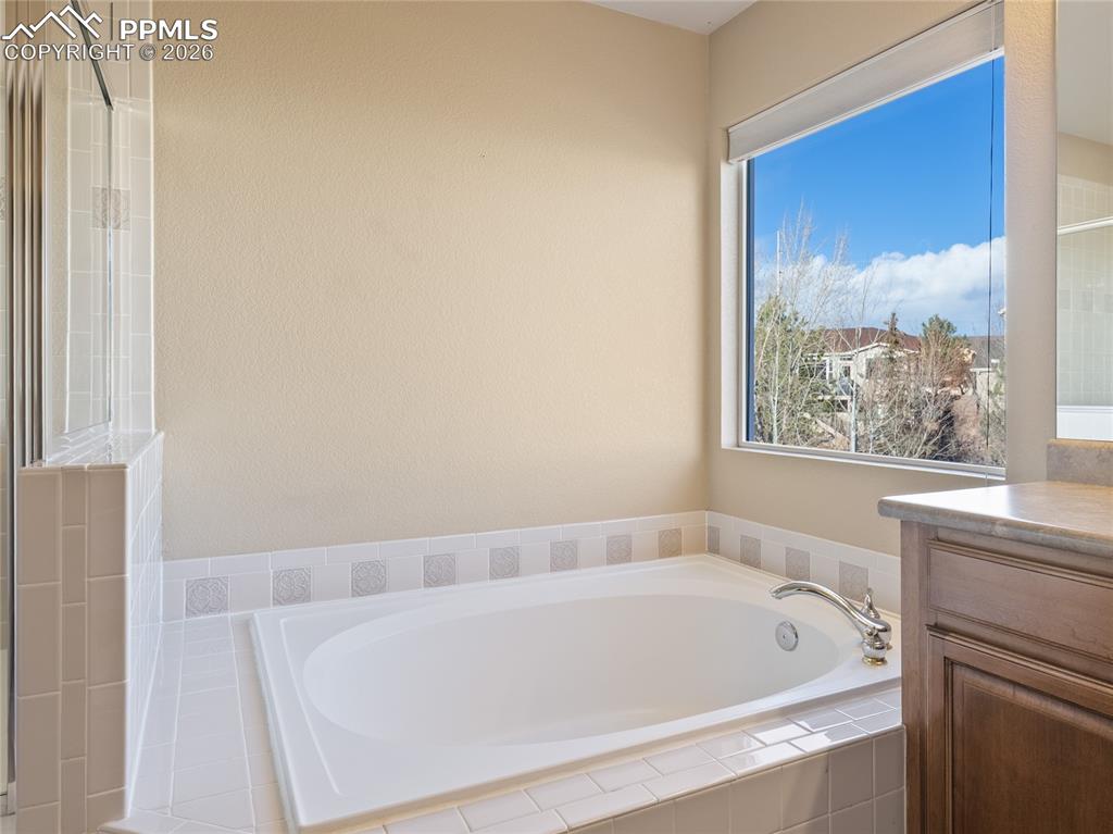 Full bath with a garden tub, vanity, and a shower with shower door