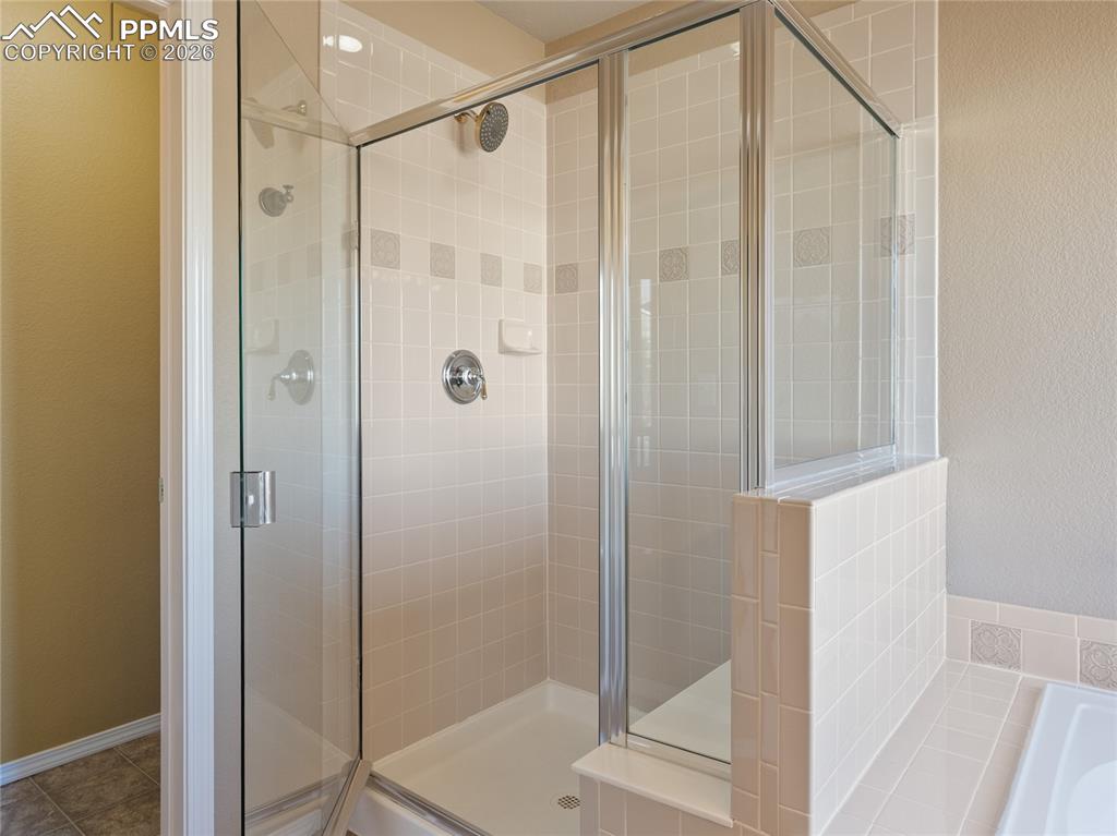 Bathroom with a shower stall, a bath, and a textured wall
