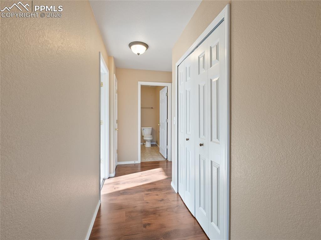 Corridor with a textured wall and dark wood-type flooring