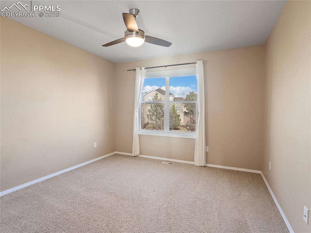 Upper level bedroom featuring carpet floors and a ceiling fan