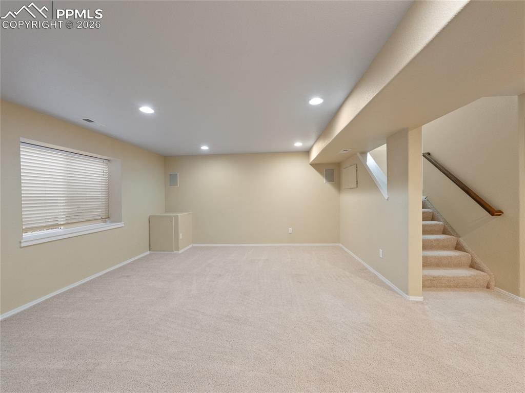 Below grade area with light colored carpet and recessed lighting