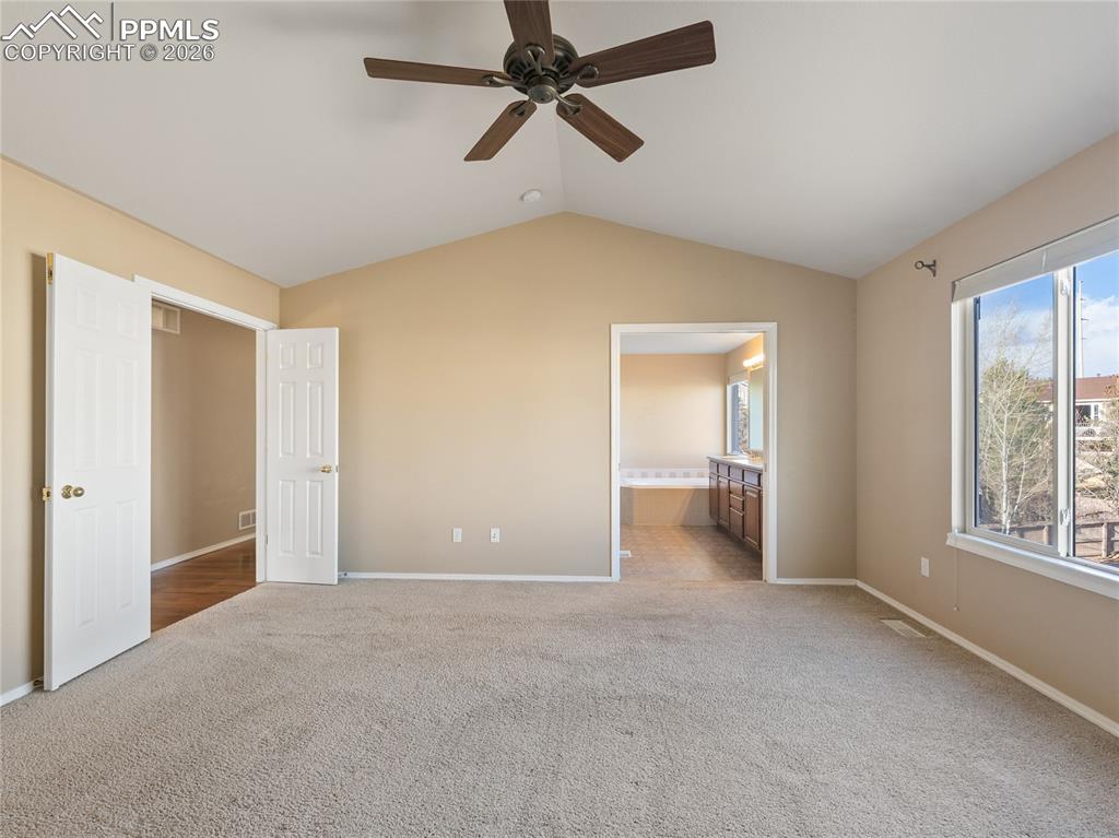Unfurnished bedroom featuring ensuite bathroom, light colored carpet, and ceiling fan