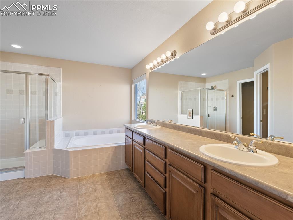 Bathroom featuring a shower stall, double vanity, a garden tub, and recessed lighting