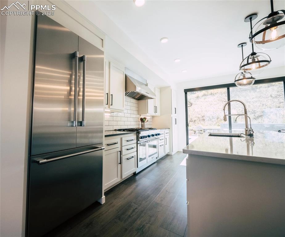 Kitchen featuring white cabinetry, stainless steel appliances, a breakfast bar, decorative backsplash, and recessed lighting
