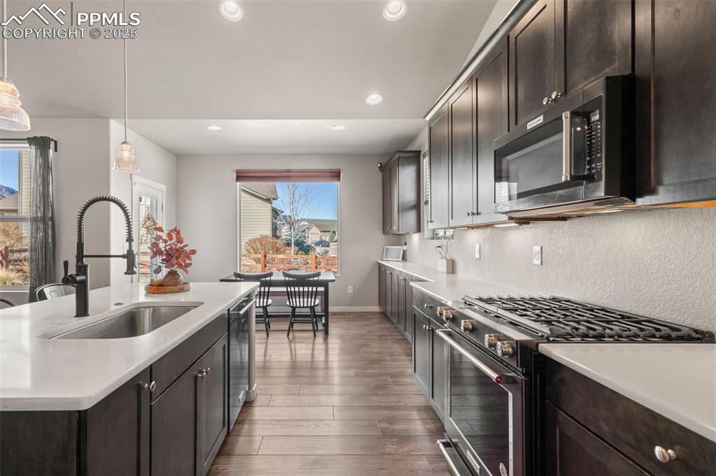 Kitchen featuring stainless steel appliances, dark brown cabinetry, pendant lighting, recessed lighting, and dark wood finished floors
