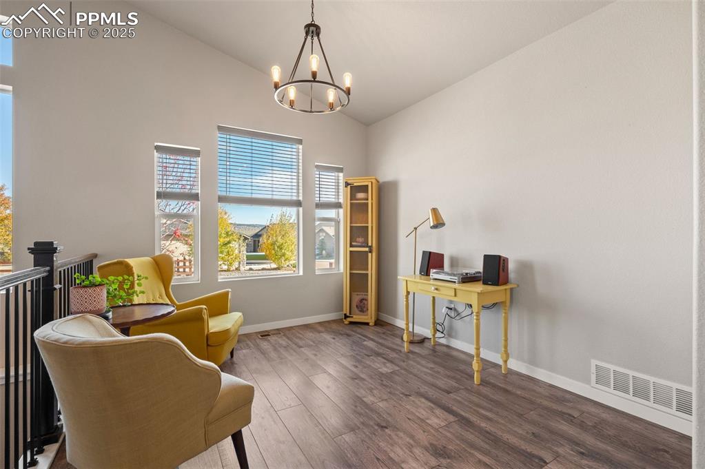 Living area featuring wood finished floors, vaulted ceiling, and a chandelier