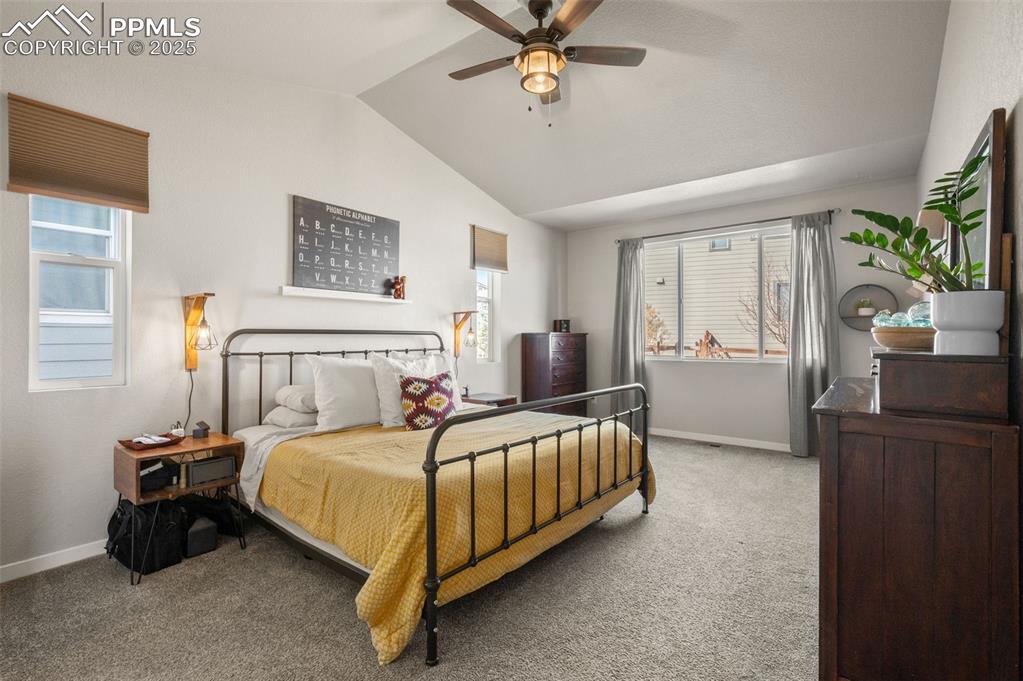 Bedroom with carpet floors, multiple windows, lofted ceiling, and a ceiling fan