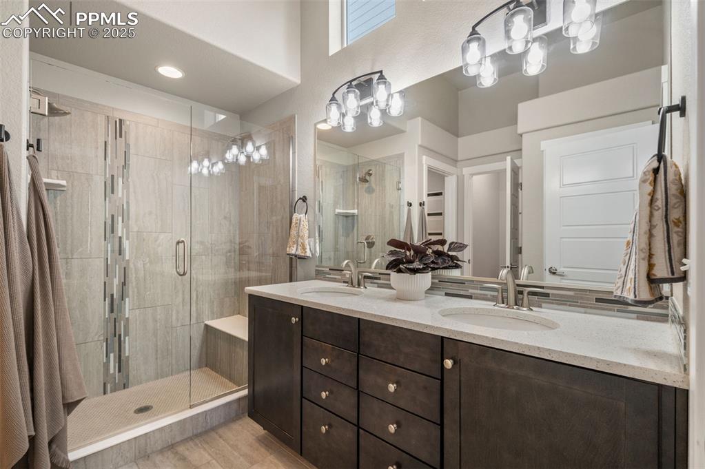Full bathroom featuring double vanity and a shower stall