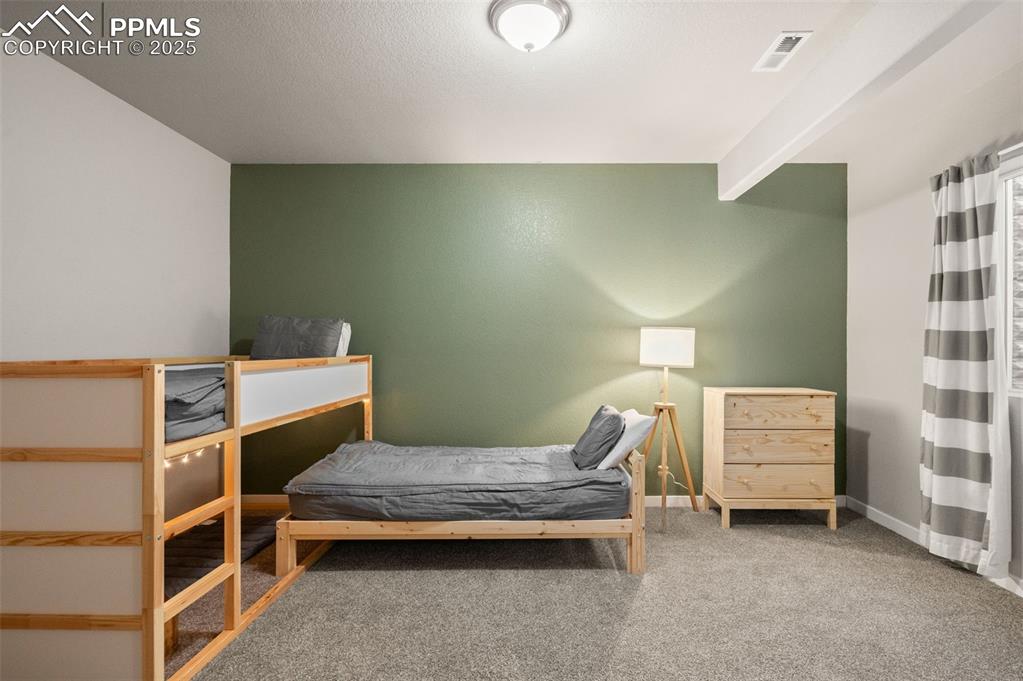 Carpeted bedroom featuring beamed ceiling and baseboards