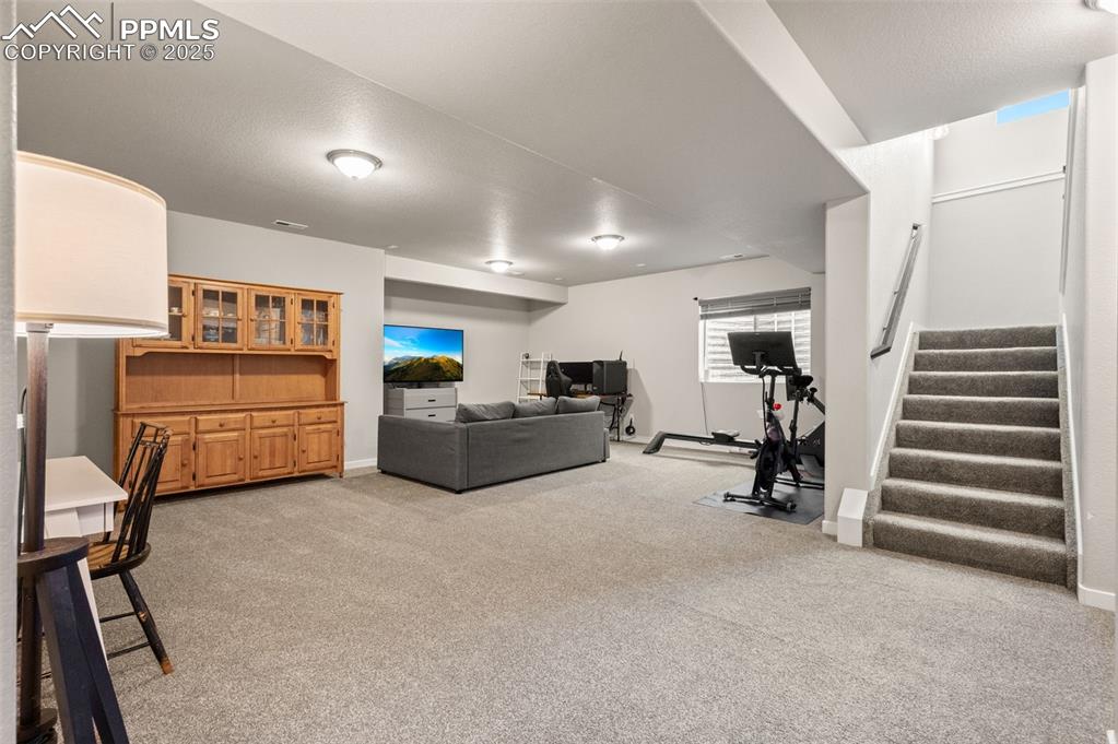 Living area with light colored carpet and stairs