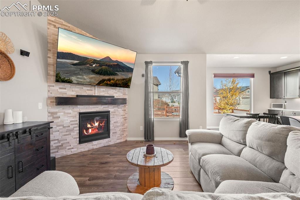 Living area featuring wood finished floors, healthy amount of natural light, a large fireplace, recessed lighting, and lofted ceiling
