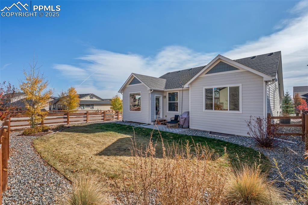 View of front of home featuring a shingled roof, a patio, and a fenced backyard