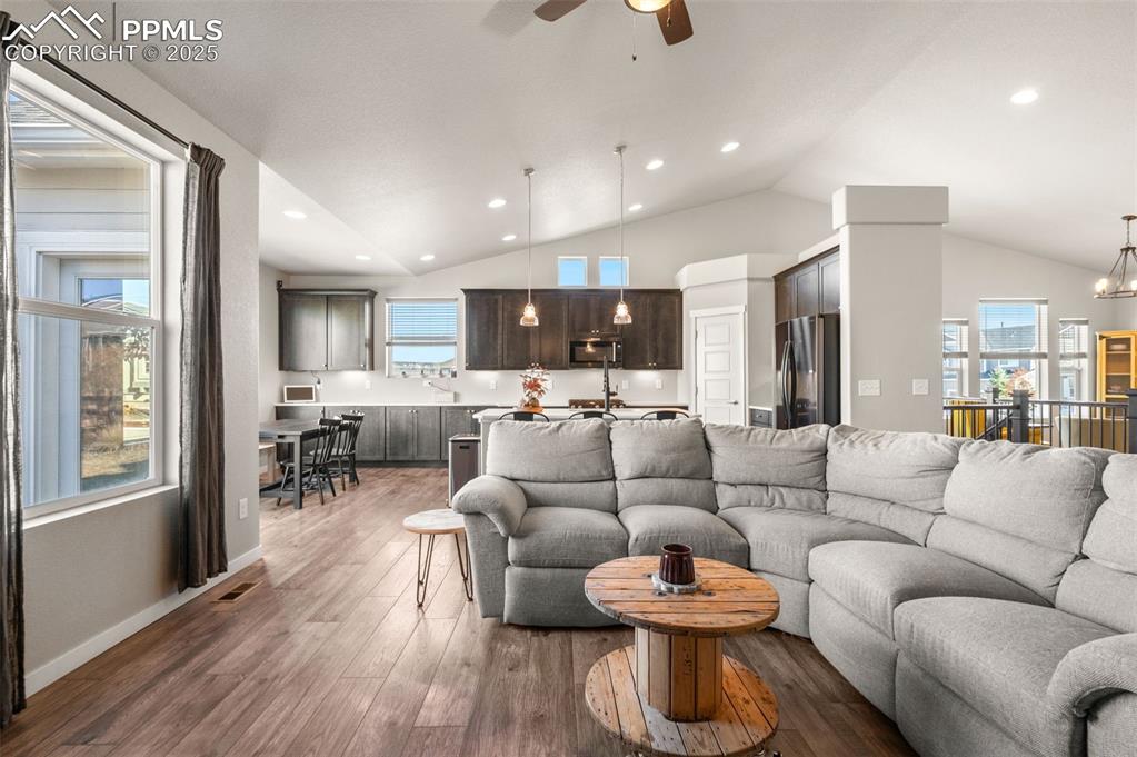 Living area with a chandelier, dark wood-style floors, healthy amount of natural light, a ceiling fan, and recessed lighting