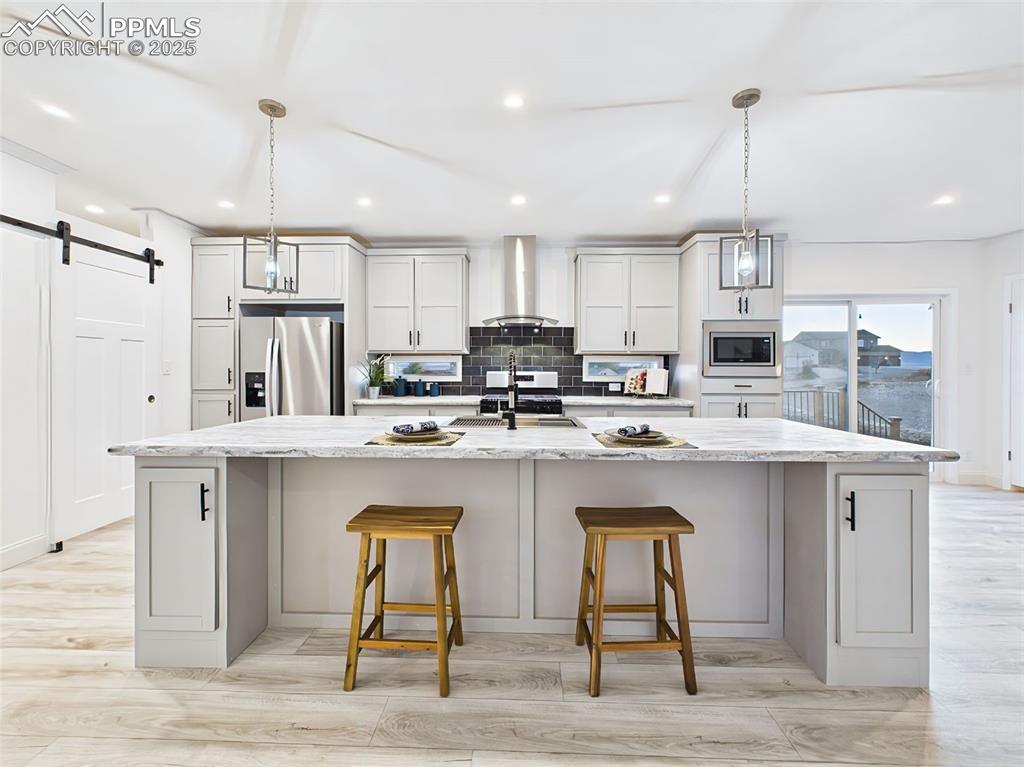 Spacious gourmet kitchen featuring a large center island, stainless steel appliances, and sleek pendant lighting.