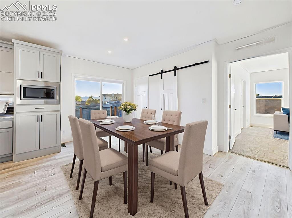 Virtually Staged dining area showing seamless flow to the kitchen and deck with lake views.