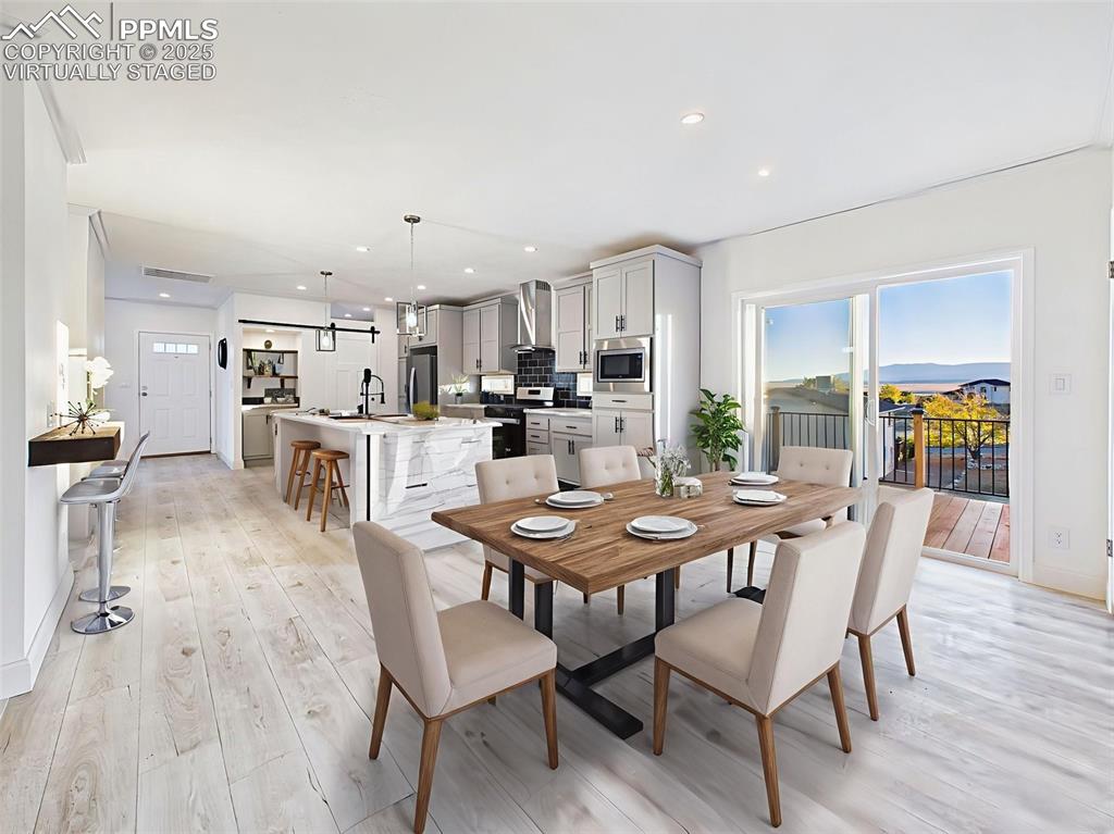 Virtually staged dining area showing seamless flow to the kitchen and deck with lake views.