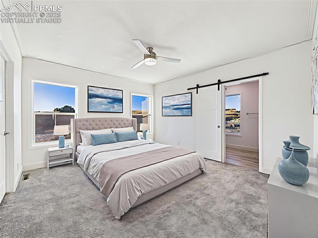 Virtually Staged Spacious primary suite with bright natural light, plush carpeting, and barn door access to ensuite bath.