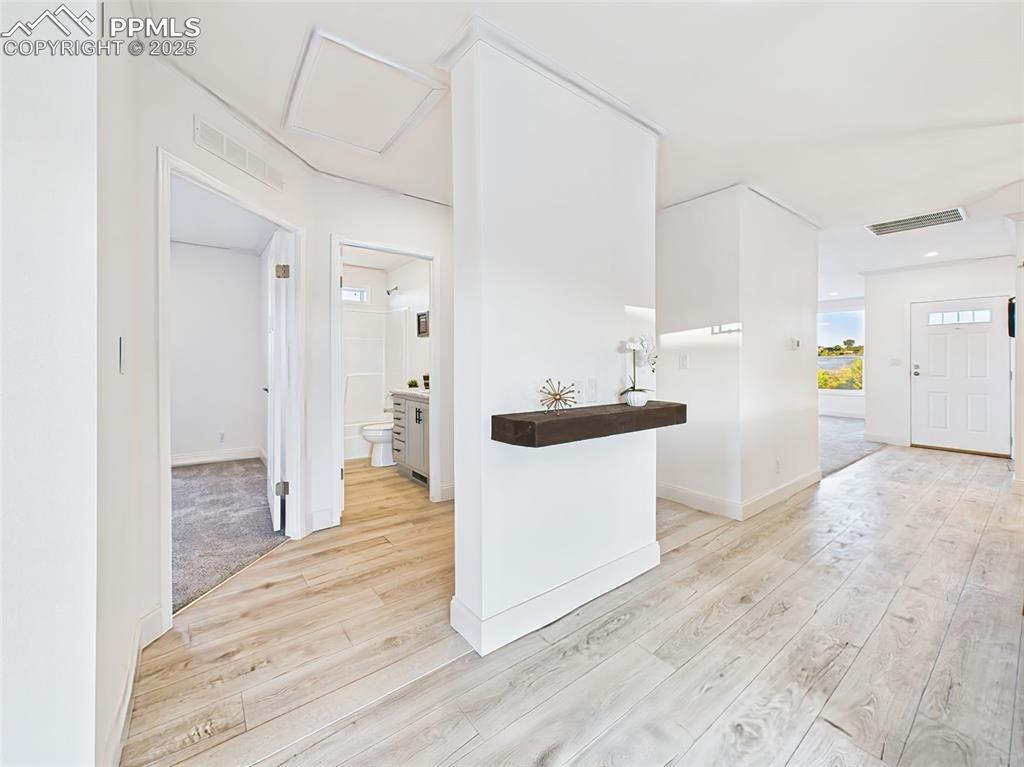Open hallway with light wood flooring leading to guest rooms and bath.