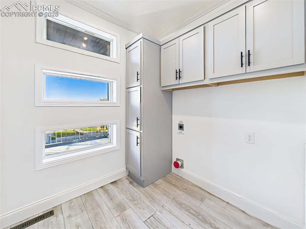 Dedicated laundry space with custom cabinetry, and unique window detail adding natural light.