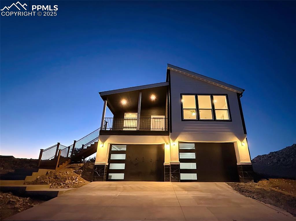 Beautifully lit twilight view showcasing the modern architectural design, covered entry, and oversized two-car garage.
