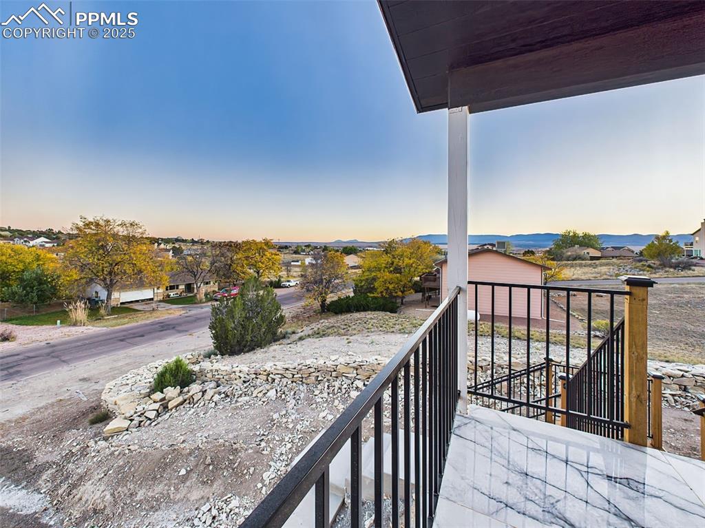 Expansive elevated view from the covered porch capturing neighborhood scenery and mountain backdrop.