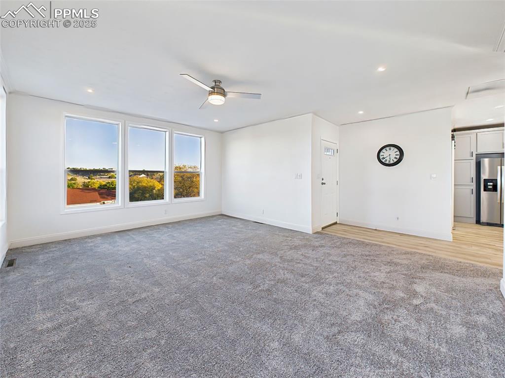Unstaged version of the main living area, highlighting the fresh paint, new carpet, and seamless flow into the kitchen.