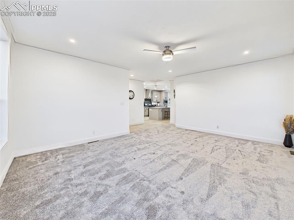 Un-staged version of the main living area, highlighting the fresh paint, new carpet, and seamless flow into the kitchen.