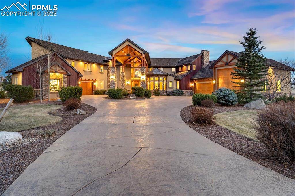 Tall timbers and rugged stone are framed by established landscaping that brings year-round color and natural beauty