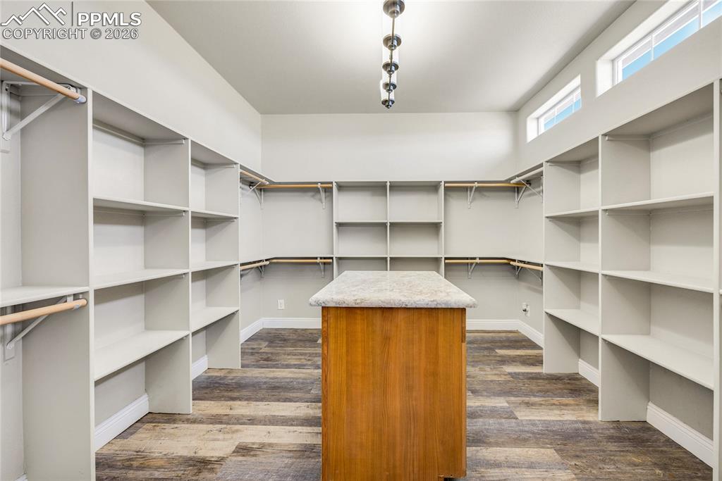 Walk in closet with dark wood finished floors