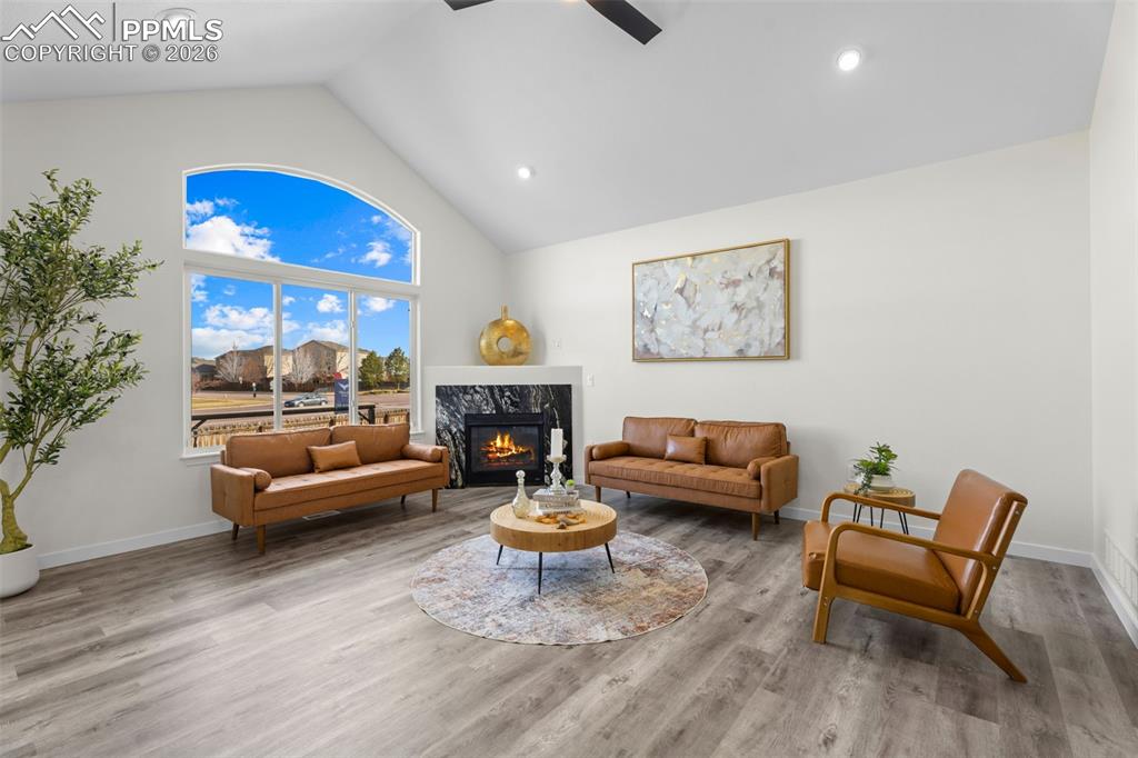 Sitting room featuring a premium fireplace, a high ceiling, a ceiling fan, light wood finished floors, and recessed lighting