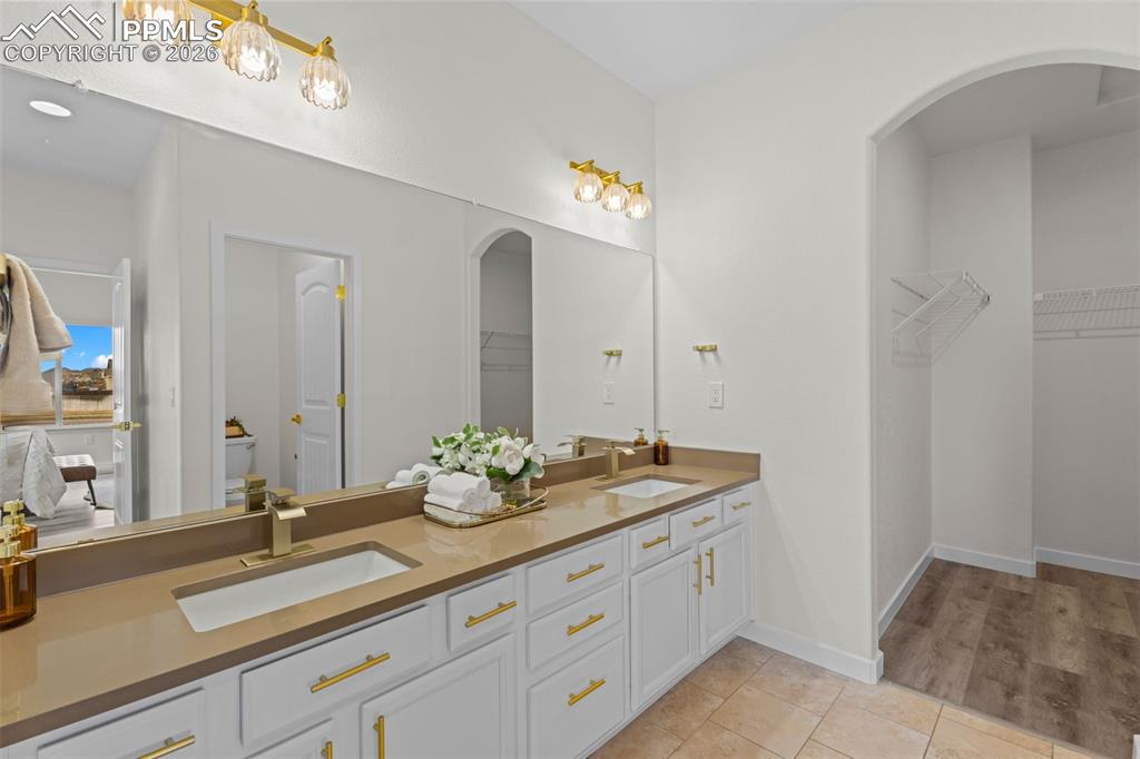 Bathroom featuring a spacious closet, double vanity, and light tile patterned floors