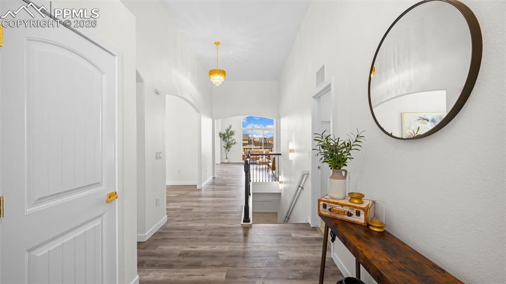 Hallway featuring dark wood finished floors, an upstairs landing, and arched walkways